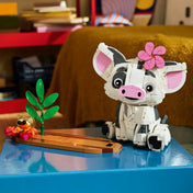 LEGO Disney: Pua 43292, 885 darabos készlet megépített Pua figurája trópusi talapzaton, pálmalevelekkel, virággal és egy kis rák figurával, dekoratív kiállítási környezetben.
