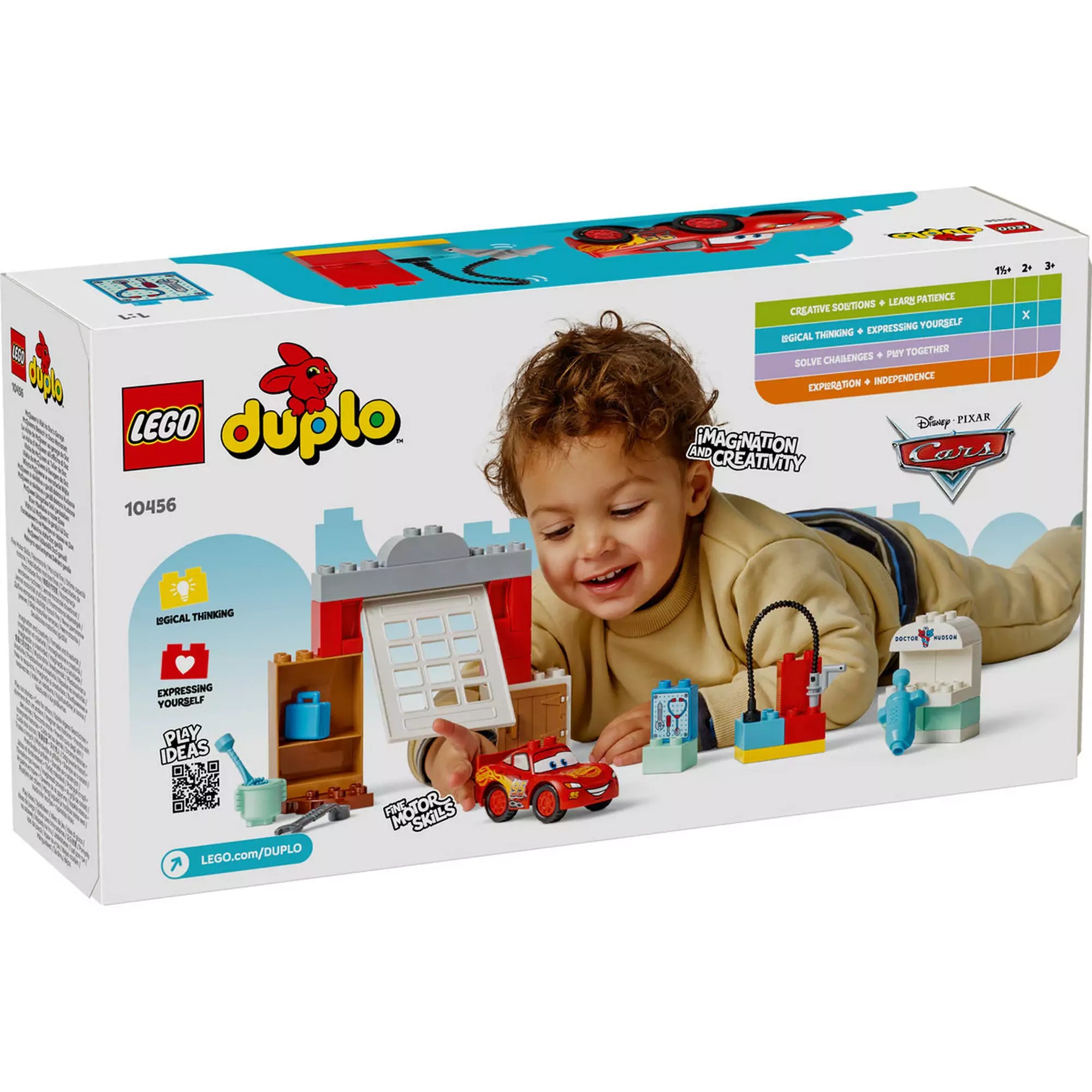 A LEGO DUPLO McQueen látogatása Doc garázsában (10456) doboz hátoldala, egy mosolygó kisfiú játszik a készlet elemeivel a padlón fekve.