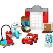 A LEGO DUPLO McQueen látogatása Doc garázsában (10456) összes fő eleme elrendezve: garázsajtó, eszközök, Doc Hudson rendelője, és Villám McQueen figura.