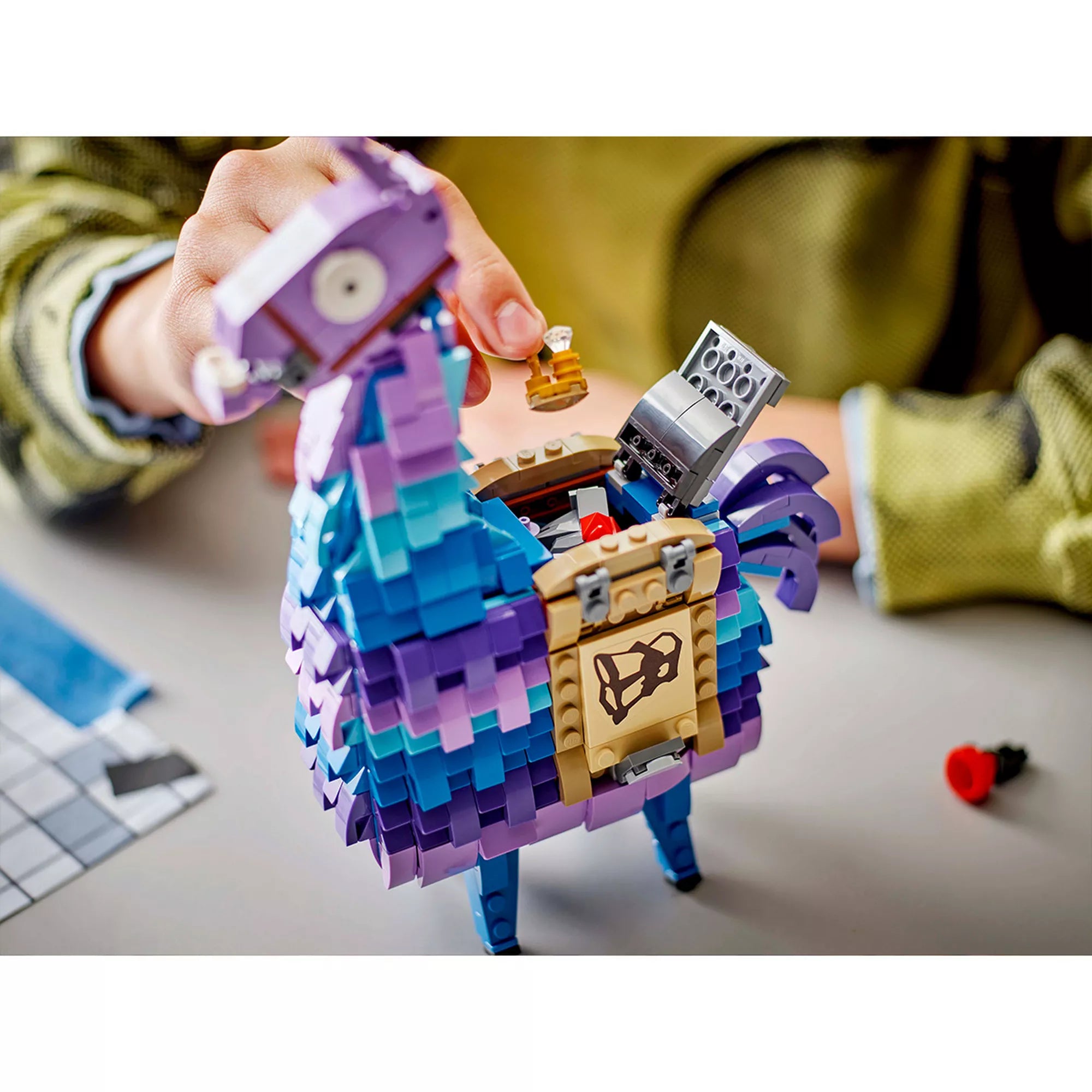 Közelkép a LEGO Fortnite Supply Llama nyitható testéről, amelybe különféle kiegészítő elemek – például italok, felszerelések és egy mini láda – helyezhetők. A részletgazdag építés jól látható.