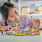 Kislány a LEGO Friends aquapark készlettel játszik, miközben az állatfigurák a csúszdát és a szökőkutat használják.