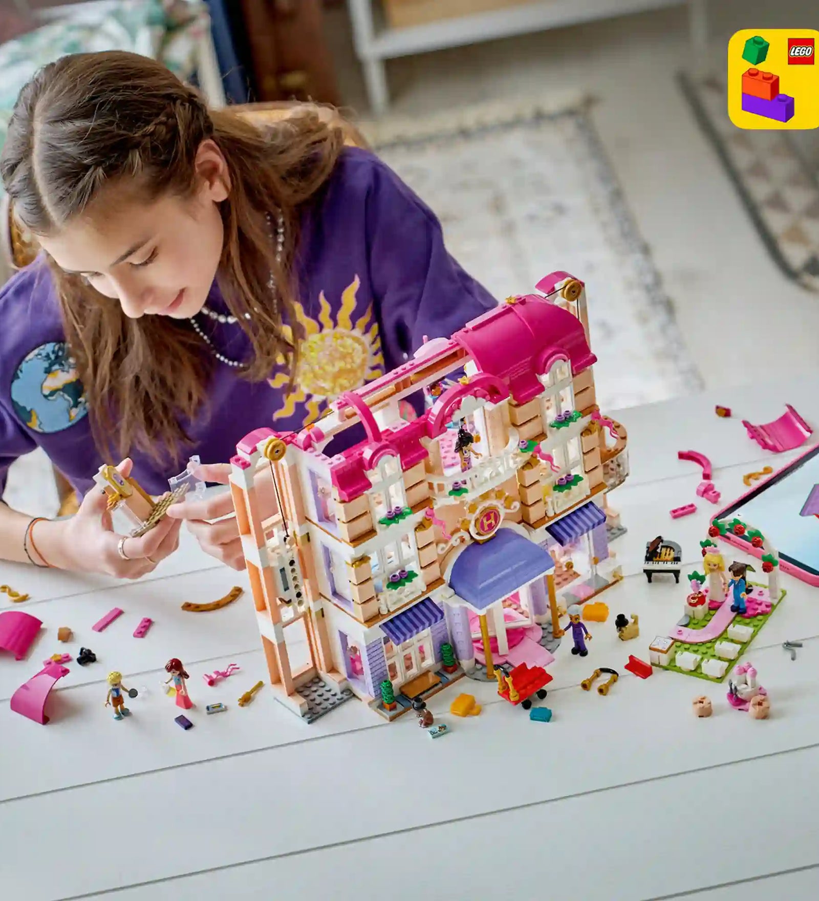Gyermek építi a LEGO Friends Heartlake City Grand Hotel szállodát, miközben a LEGO Builder alkalmazás digitális útmutatóját használja.
