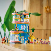 LEGO Friends Heartlake City barátságklub teljes egészében felépítve, háromszintes klubépülettel, csúszdával, erkélyekkel, figurákkal és állatfigurákkal egy asztalon.