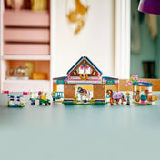 LEGO Friends Lovasistálló és lovasakadémia teljes egészében felépítve, istállóval, kifutóval, ugrató akadályokkal, lovakkal és figurákkal egy asztalon.