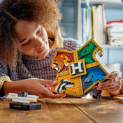LEGO Harry Potter: A Roxfort címere 76462, 545 darabos készlet játék közben, ahol egy gyermek a részletgazdag címert tartja, amely a Roxfort négy házának állatait ábrázolja.