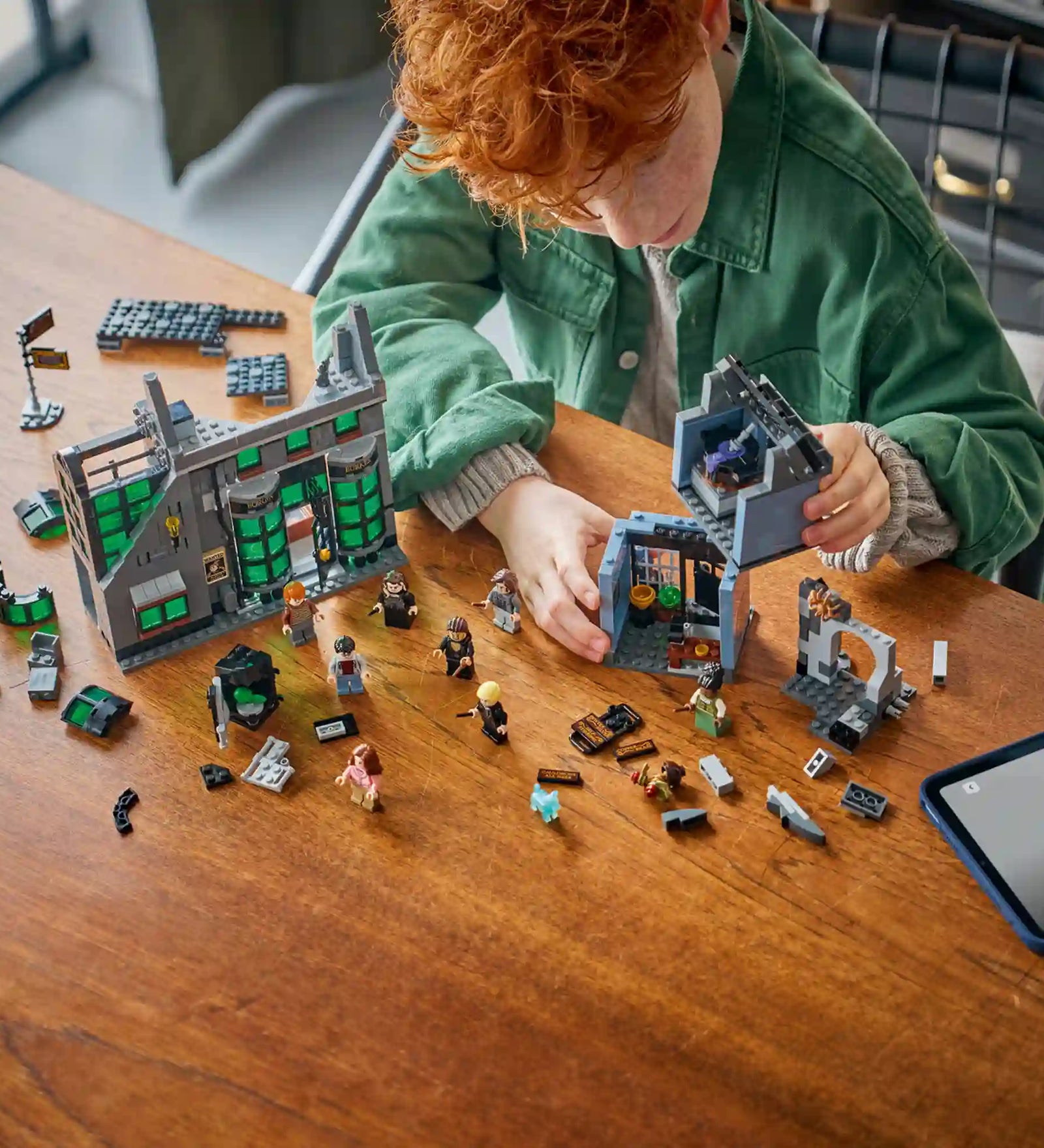 LEGO Harry Potter 76471 építési jelenet vörös hajú gyermekkel, aki a Borgin és Burkes és az Üstbolt moduljait szereli össze.