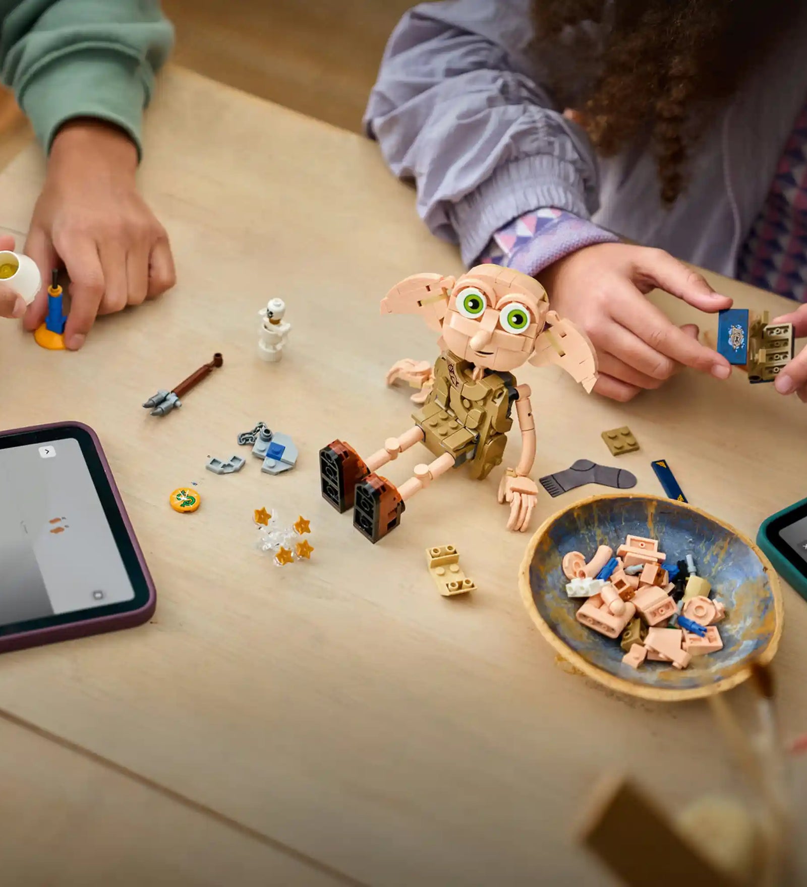LEGO Harry Potter Dobby, a szabad manó 76469 építés közben egy asztalon, körülötte Harry Potter kiegészítők, Tom Denem naplója, lámpa és varázslatos elemek.