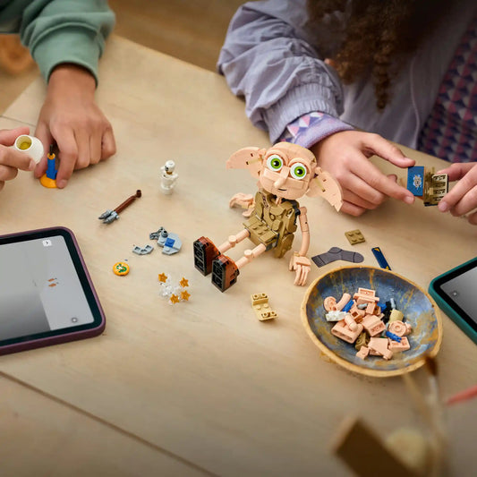 LEGO Harry Potter Dobby, a szabad manó 76469 építés közben egy asztalon, körülötte Harry Potter kiegészítők, Tom Denem naplója, lámpa és varázslatos elemek.