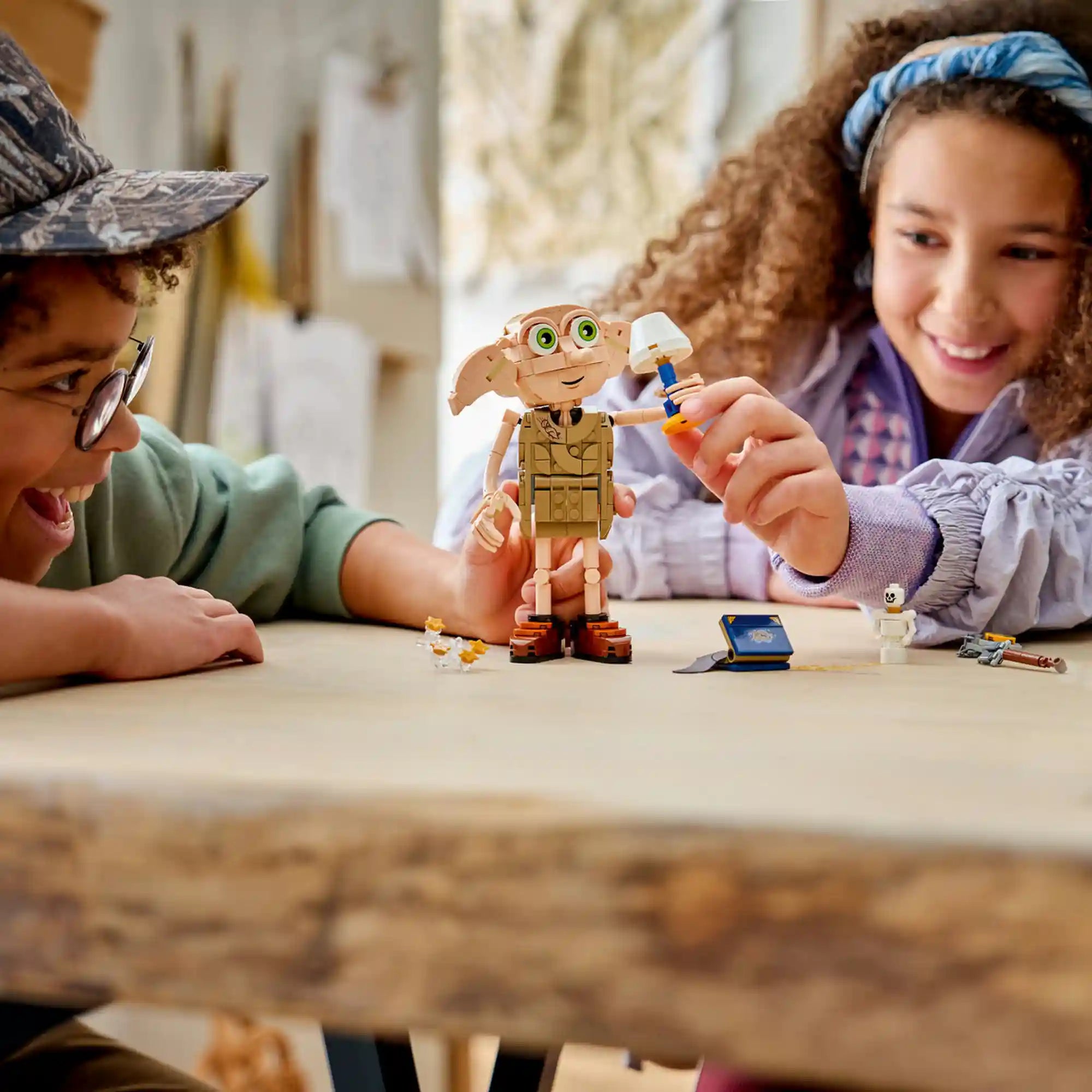 Gyerekek játszanak a LEGO Harry Potter 76469 Dobby figurával, amely mozgatható végtagokkal és ikonikus Harry Potter kiegészítőkkel van felszerelve.