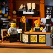 LEGO Icons (Creator Expert): Könyvkuckó Könyvesbolt 11379 kávézórészlete, kávégéppel, pulttal, baristával és kávét tartó minifigurával.