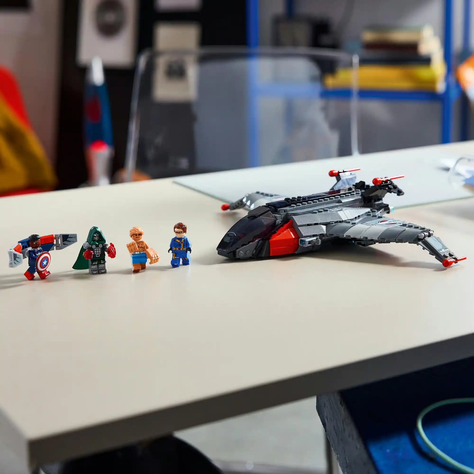 A megépített LEGO Quinjet egy fehér asztalon, mellette Amerika Kapitány, Doctor Doom, Lény és Küklopsz minifigurái.