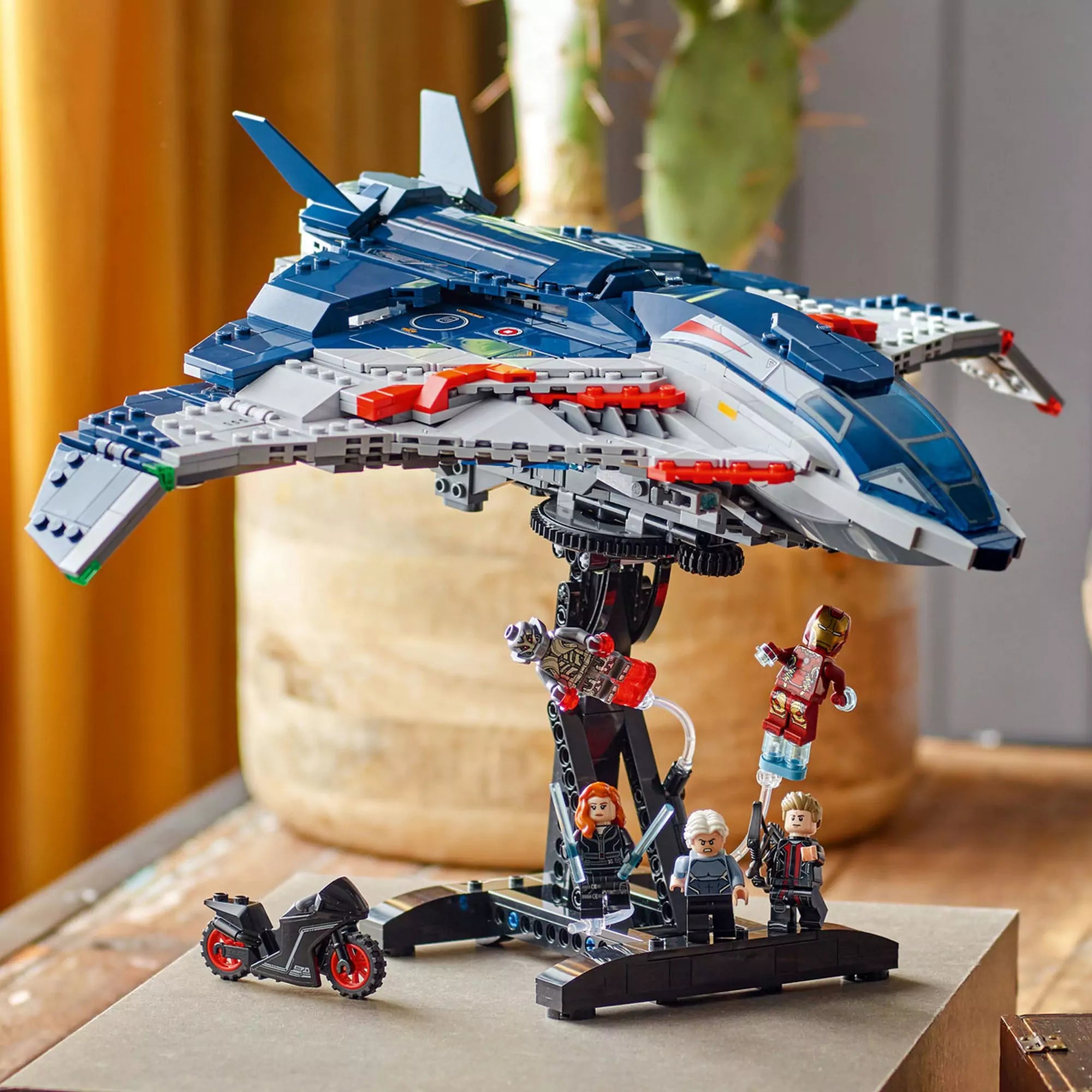 A LEGO Marvel Quinjet (76325) repülő a tartóállványon, alatta Fekete Özvegy motorral, Vasember, Ultron és Higanyszál figurái.