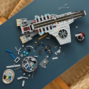 Építés alatt álló LEGO Helicarrier felülnézetből, szétszórt építőelemekkel, minifigurákkal és alkatrészekkel teli tálakkal.