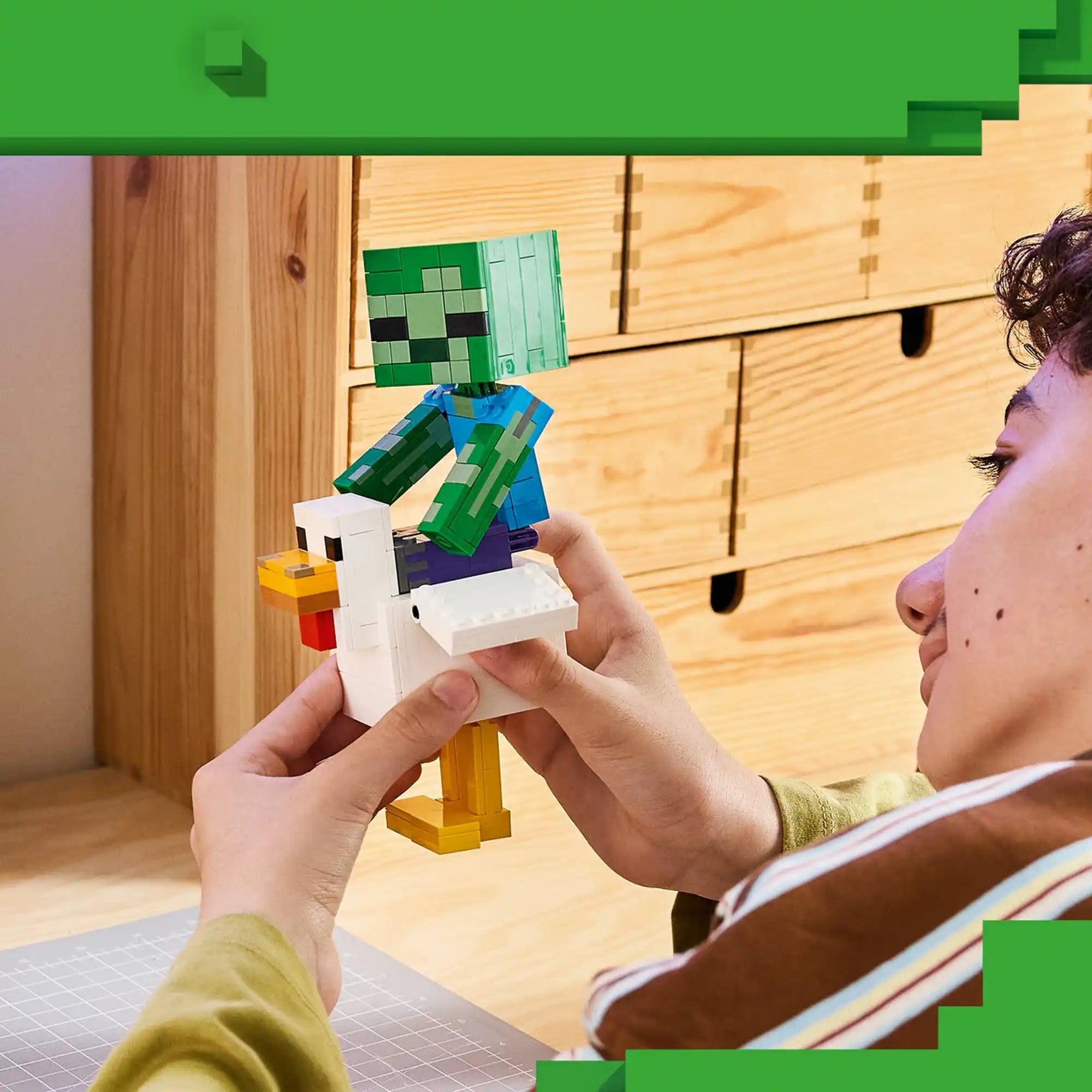 A LEGO Minecraft: Chicken Jockey 21582 készlettel játszó gyermek, aki a Zombit a Csirkére ülteti.