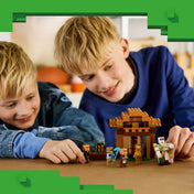 Gyerekek játszanak a LEGO Minecraft 21596 falusi jelenetével, amelyben falusiak, vasgólem és ellenséges mobok vesznek részt.