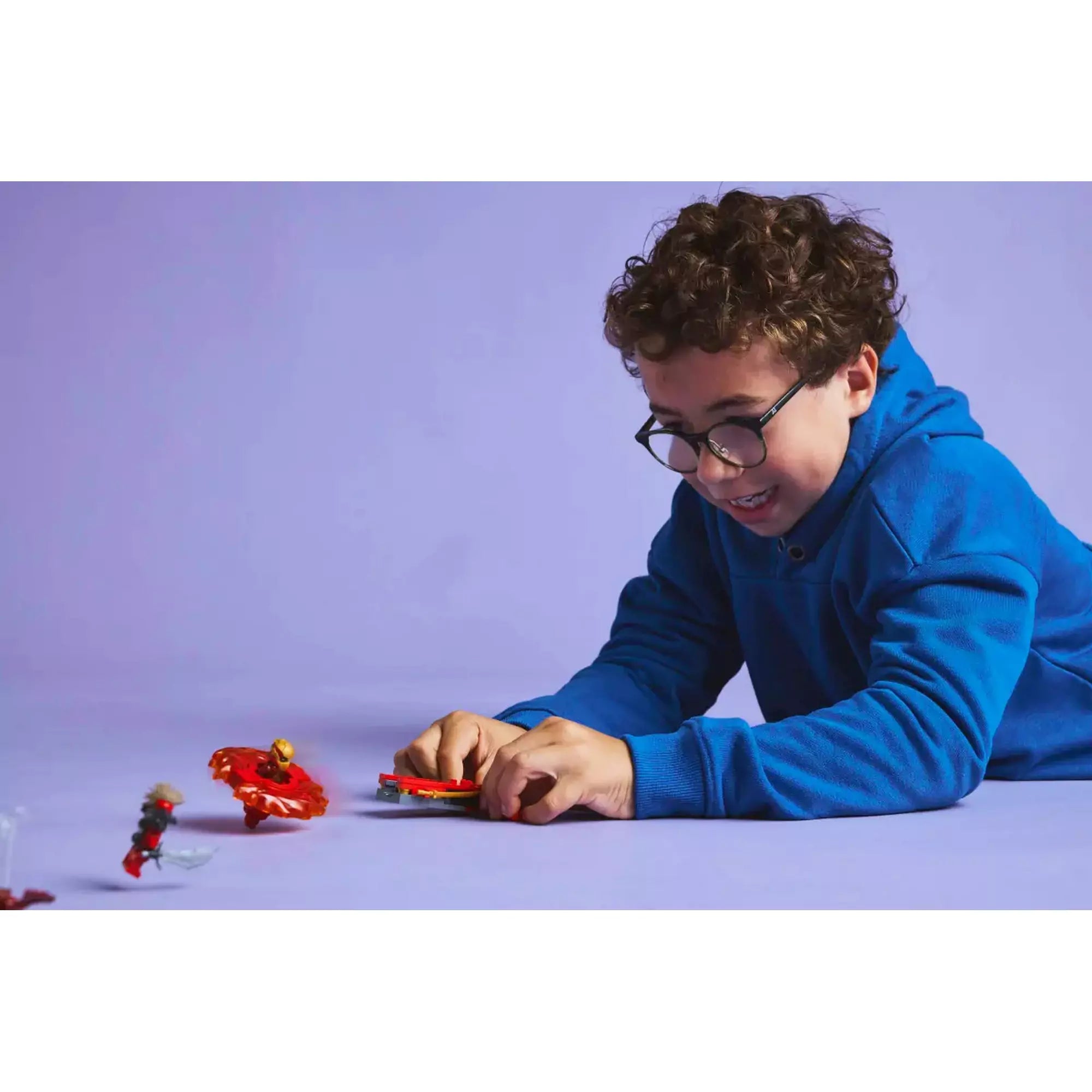  Gyerek játék közben, kipróbálva a LEGO Ninjago Kai sárkány Spinjitzu pörgettyűjének (71823) pörgési képességeit.