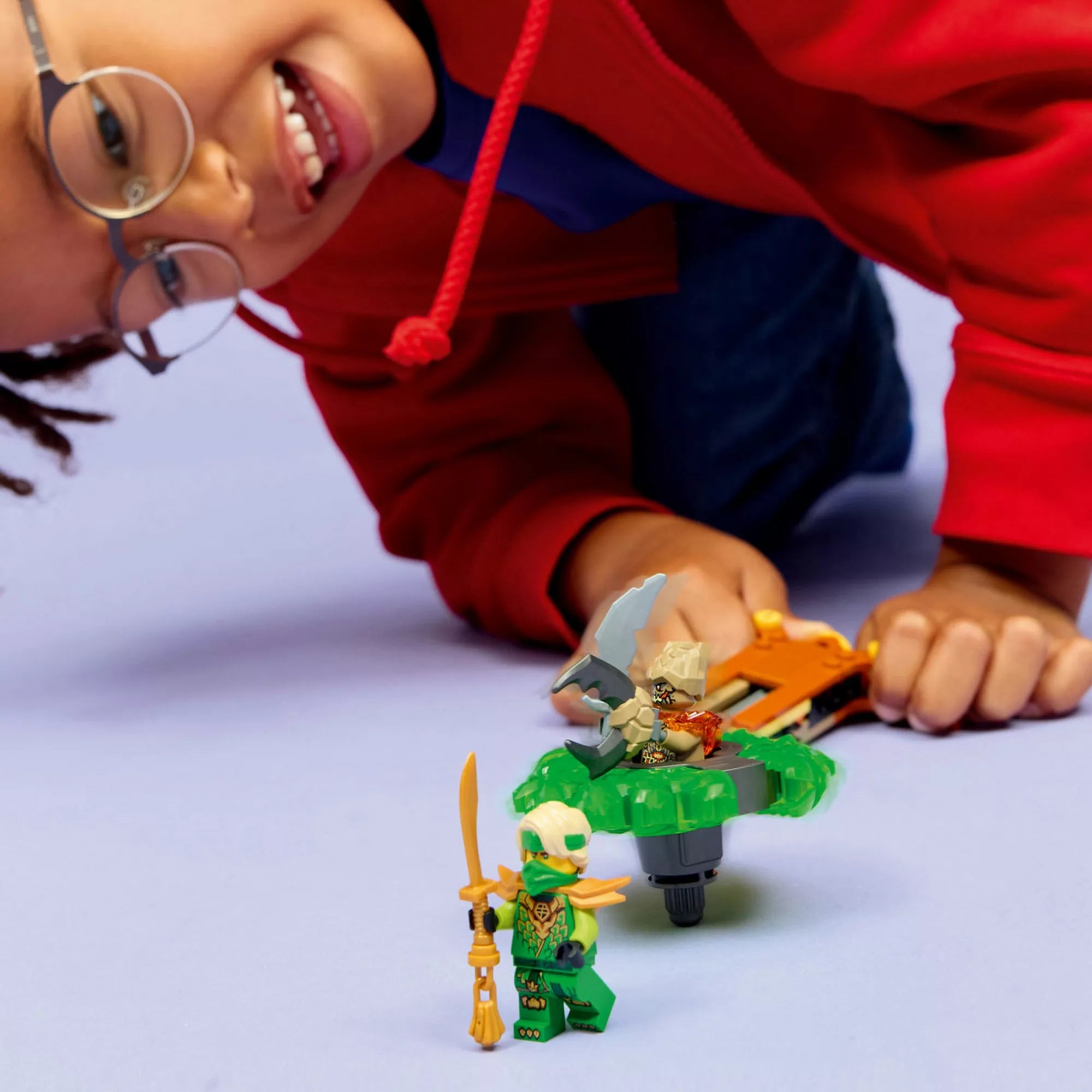 Gyermek játék közben a LEGO NINJAGO Lloyd vs. Föld Szörny pörgettyű készlettel, indítóval és minifigurákkal.