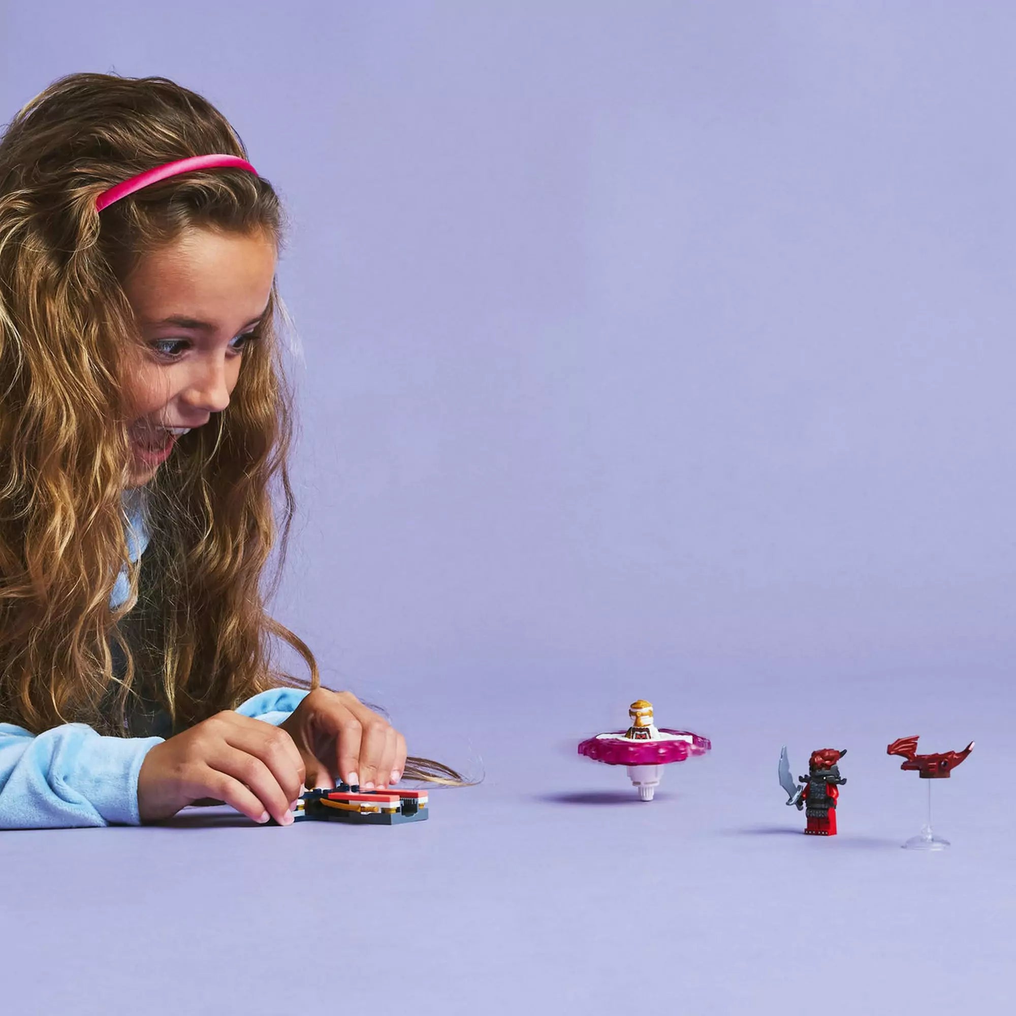 Egy gyermek örömmel figyeli a LEGO Ninjago Sora sárkány Spinjitzu pörgettyűje 71824 szett izgalmas forgását.