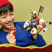 Gyermek kezében a LEGO NINJAGO Grimtak sárkányszörny modell, mellette Kai sárkányformájú minifigura, részletgazdag fantasy harci jelenet.