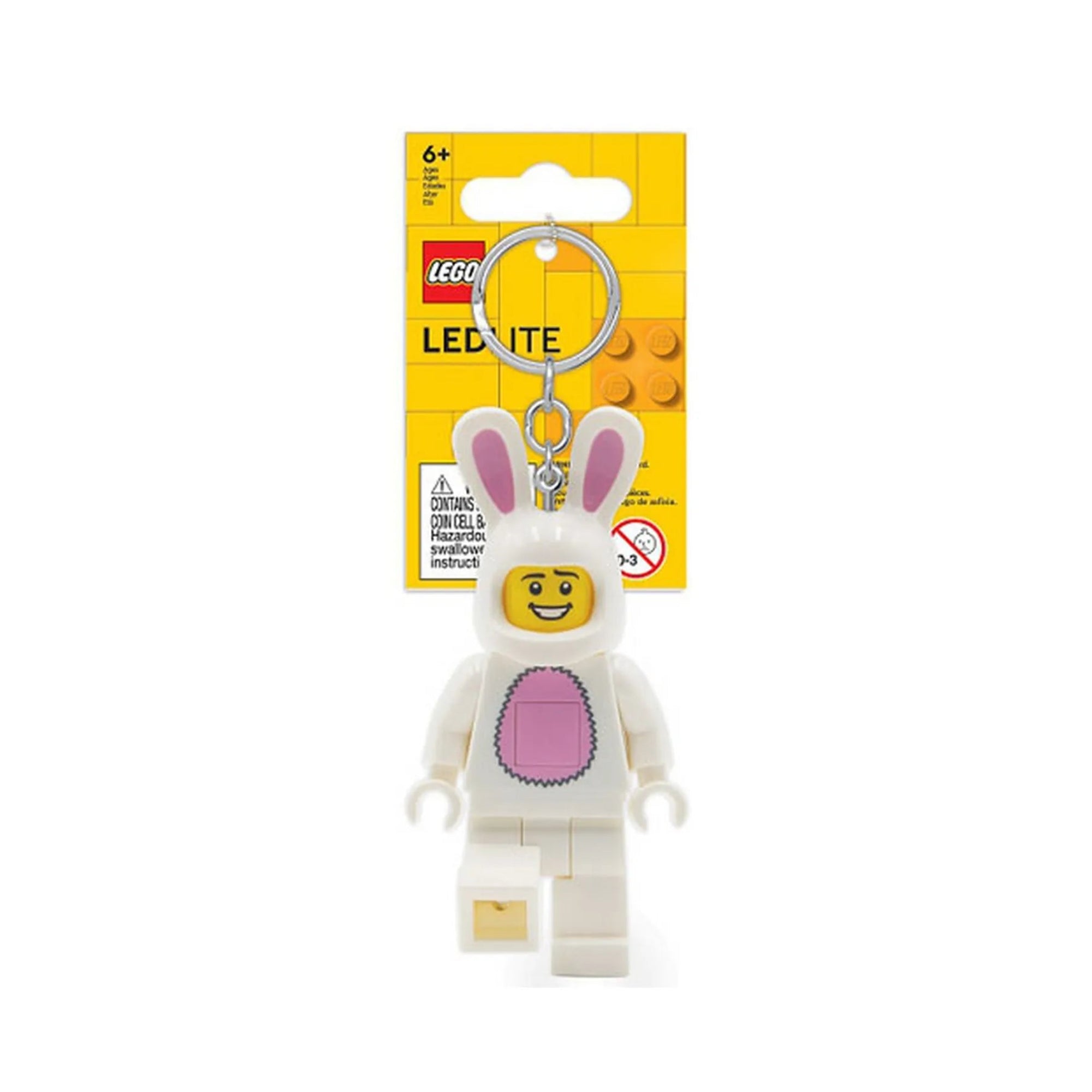 A LEGO Nyuszis minifigura LED kulcstartó csomagolva, sárga háttérlap előtt. A kulcstartón fehér nyuszijelmezbe bújt, mosolygós LEGO figura látható rózsaszín hassal és hosszú fülekkel.