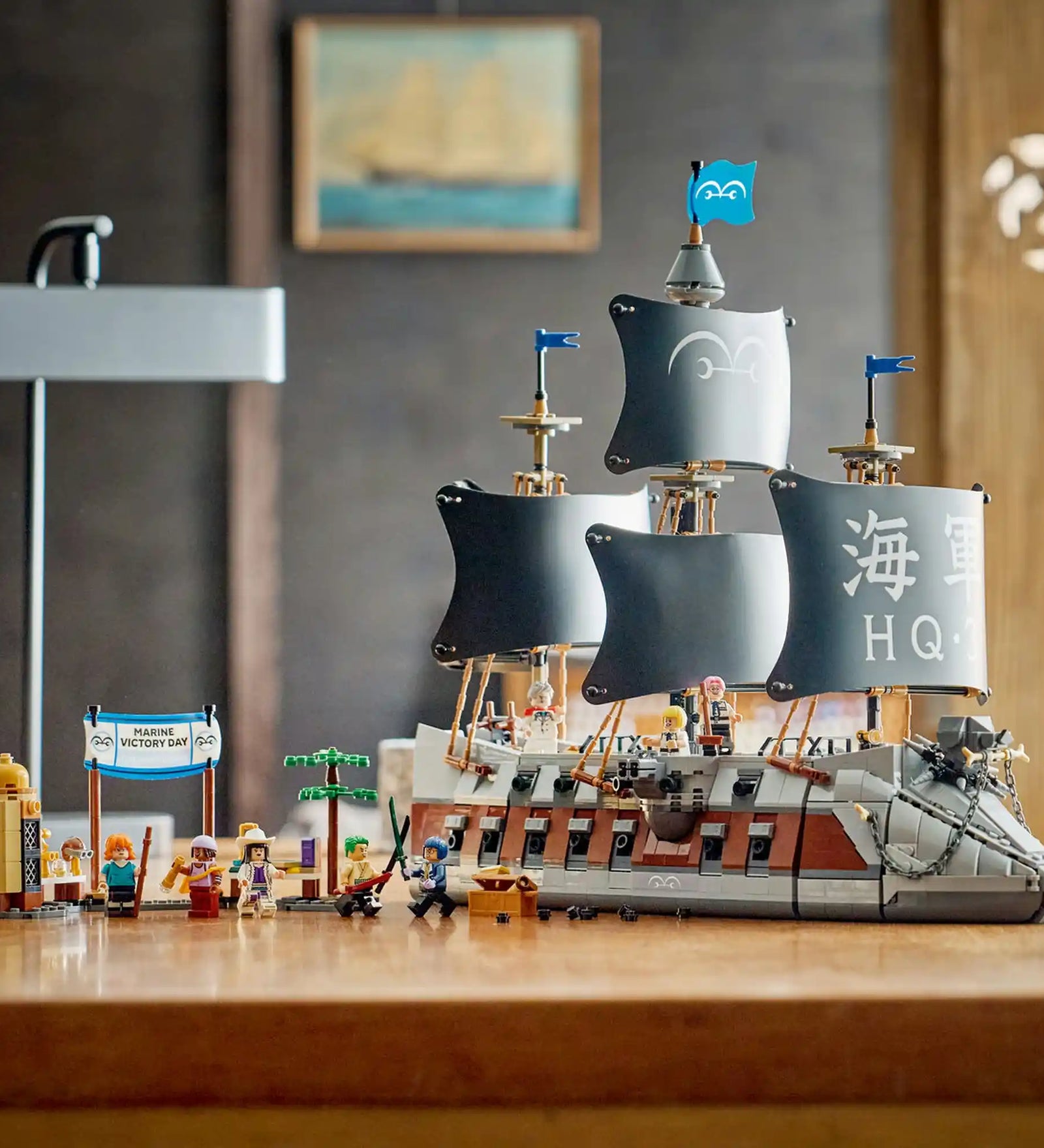 A LEGO ONE PIECE: Garp tengeri csatahajója 75646 teljesen megépített modellje a nyolc minifigurával és a Marine Victory Day díszlettel egy asztalon kiállítva.