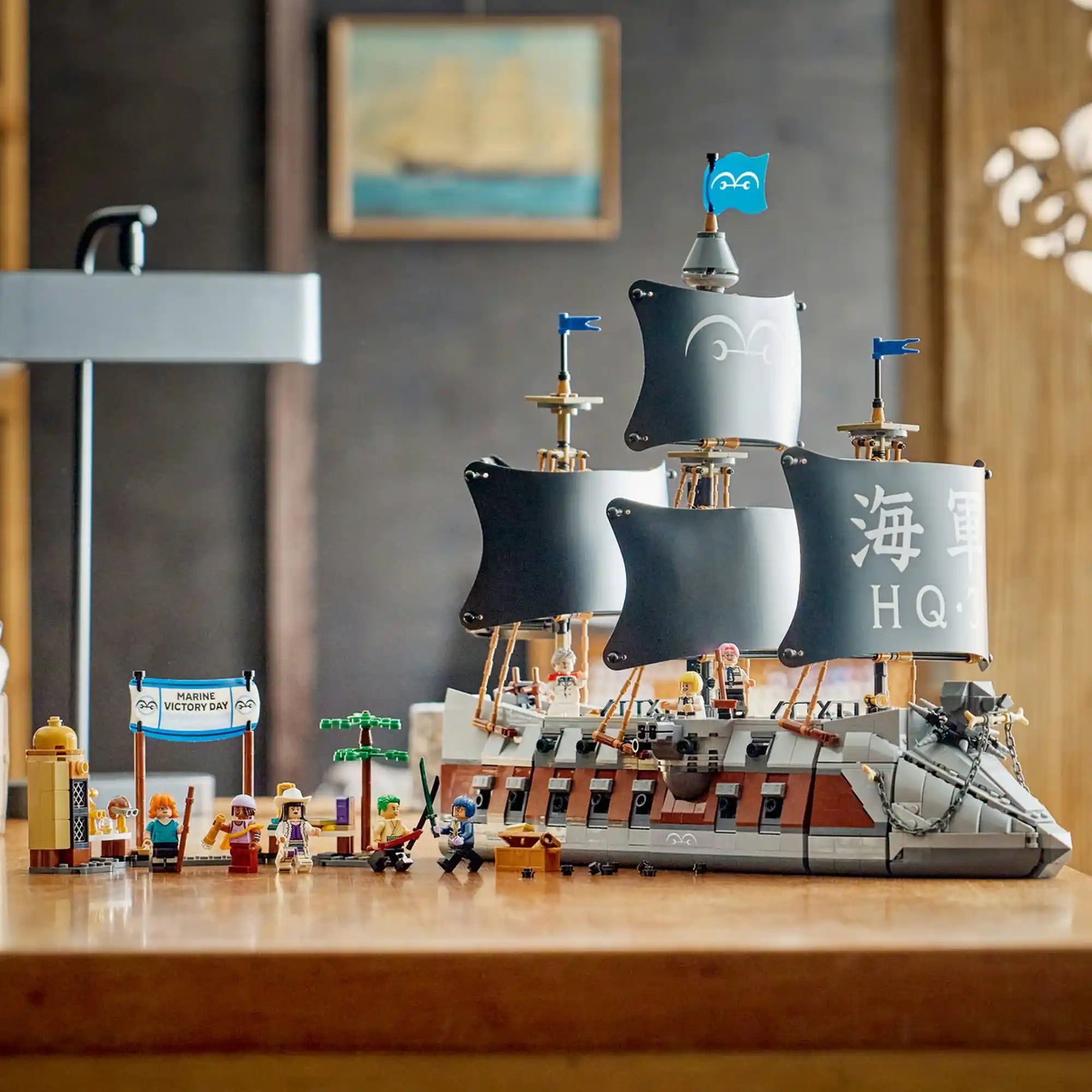 A LEGO ONE PIECE: Garp tengeri csatahajója 75646 teljesen megépített modellje a nyolc minifigurával és a Marine Victory Day díszlettel egy asztalon kiállítva.