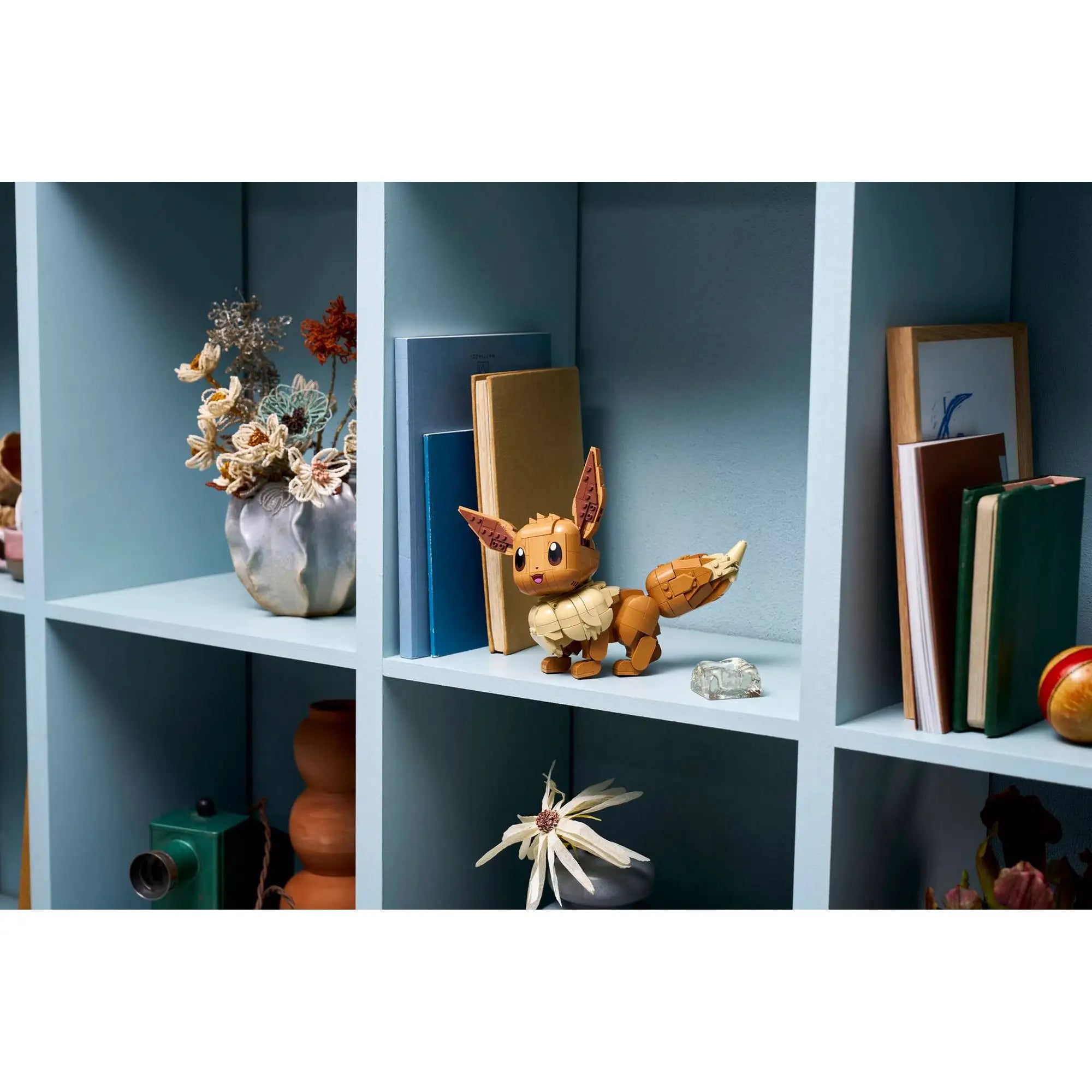LEGO Pokémon Eevee megépített figura polcon elhelyezve, dekorációként könyvek és dísztárgyak között, modern lakásbelsőben