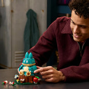 Egy építő a LEGO Pokémon Munchlax figurát állítja be a részletgazdag talapzaton.