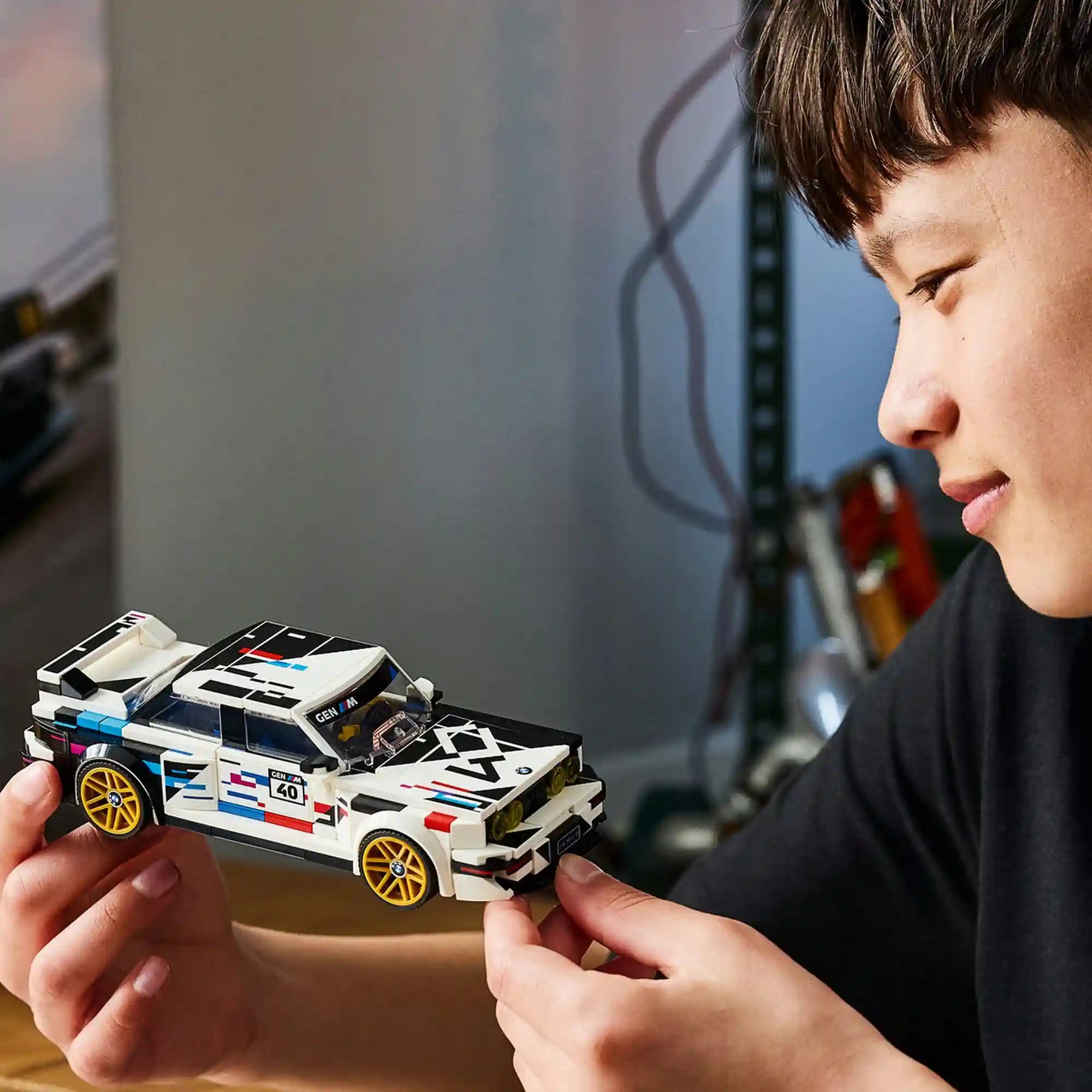 Gyermek a megépített LEGO BMW M3 (E30) modellt tartja a kezében.