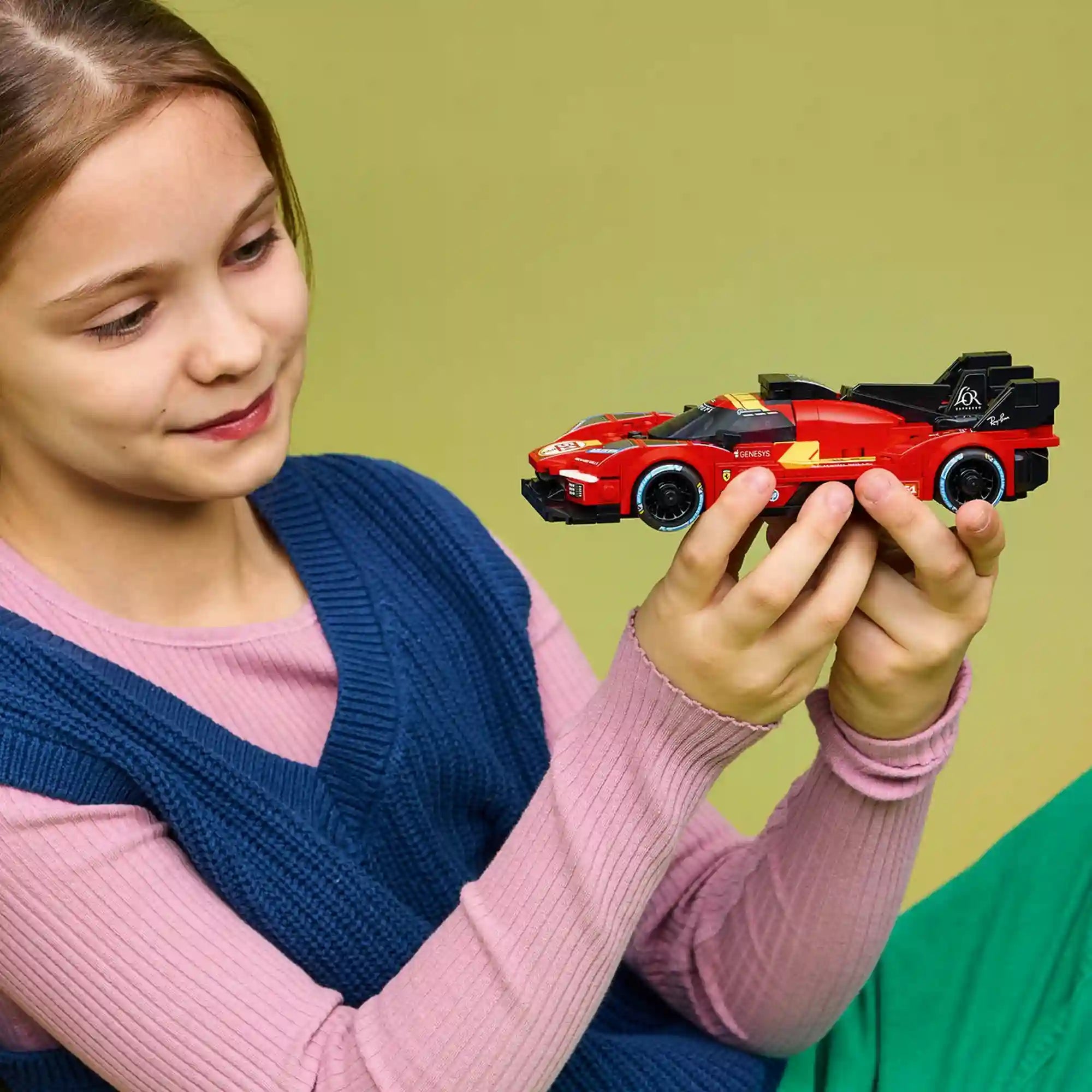 Gyermek a kezében tartja a LEGO Speed Champions Ferrari 499P versenyautó modelljét játék közben.