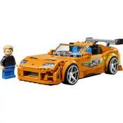 LEGO Halálos iramban Toyota Supra MK4 narancssárga versenyautó Brian O’Conner minifigurával fehér háttér előtt.