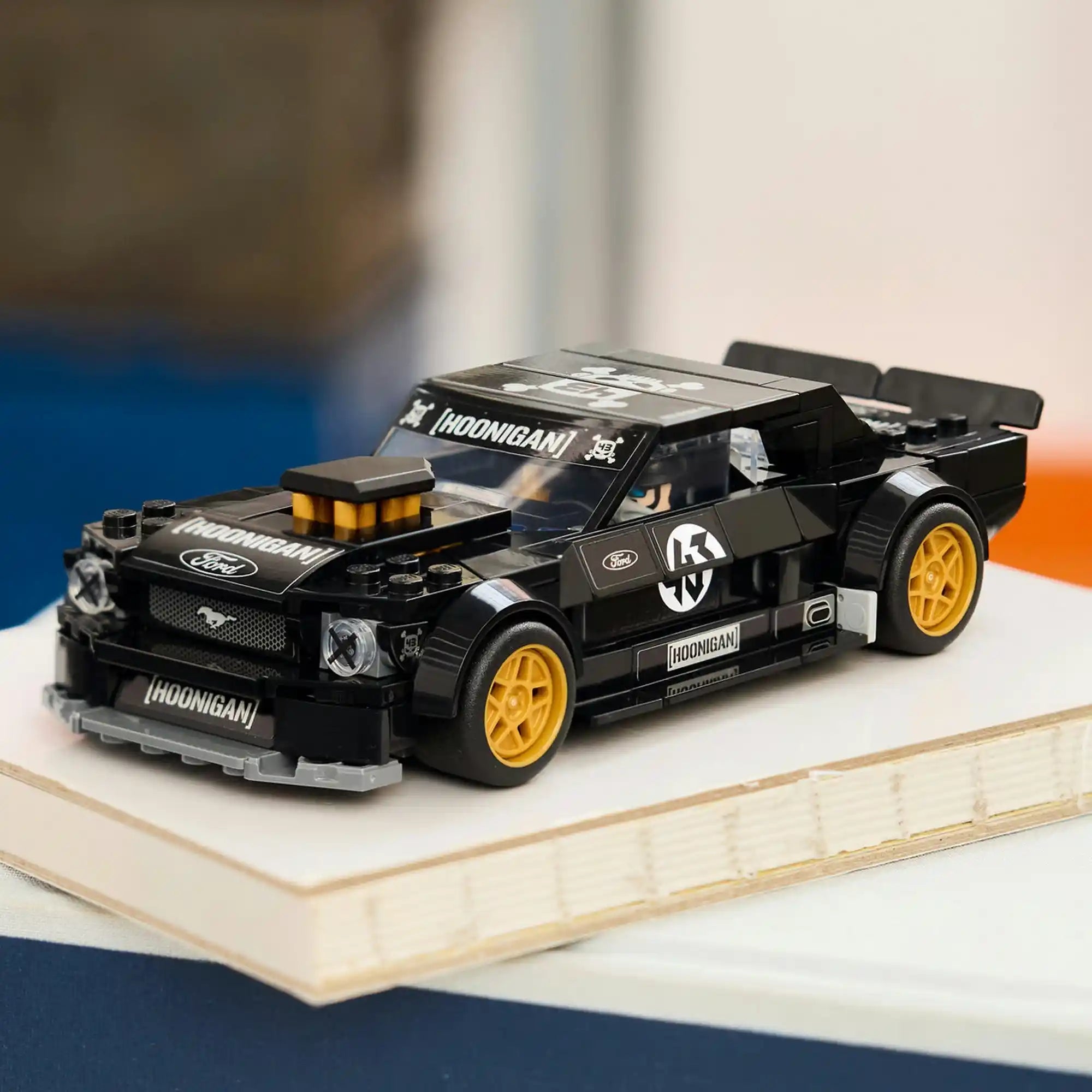 LEGO Ford Mustang Hoonicorn V1 modell fekete karosszériával és aranyszínű kerekekkel kiállítva egy asztalon.