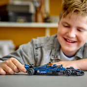 Kisfiú mosolyogva tologatja az elkészült LEGO Williams FW46 autót egy asztalon, játék közben