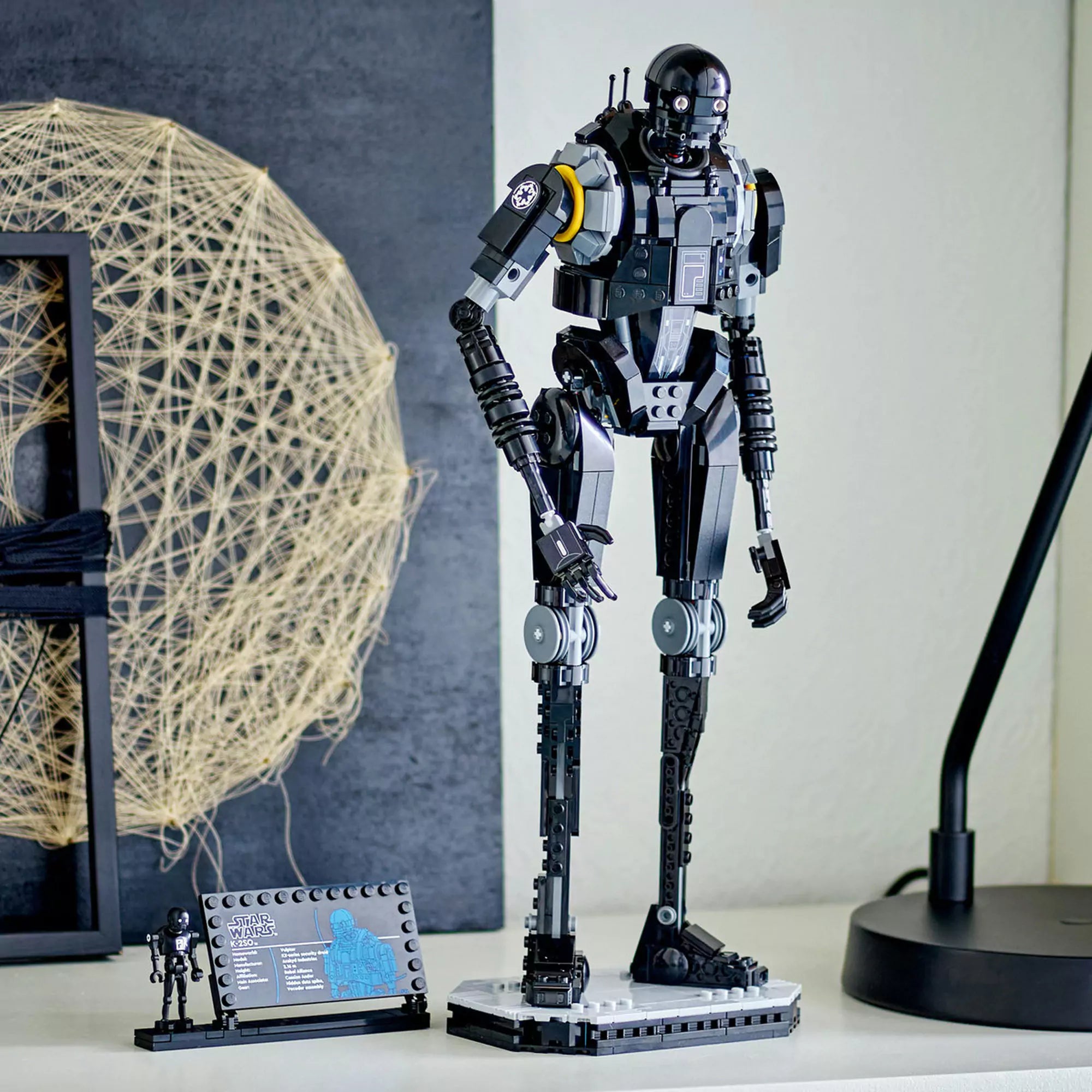 LEGO Star Wars: K-2SO biztonsági droid (75434) kiállítva – a kész modell talapzaton áll, mellette a minifigura és a névtábla látható.