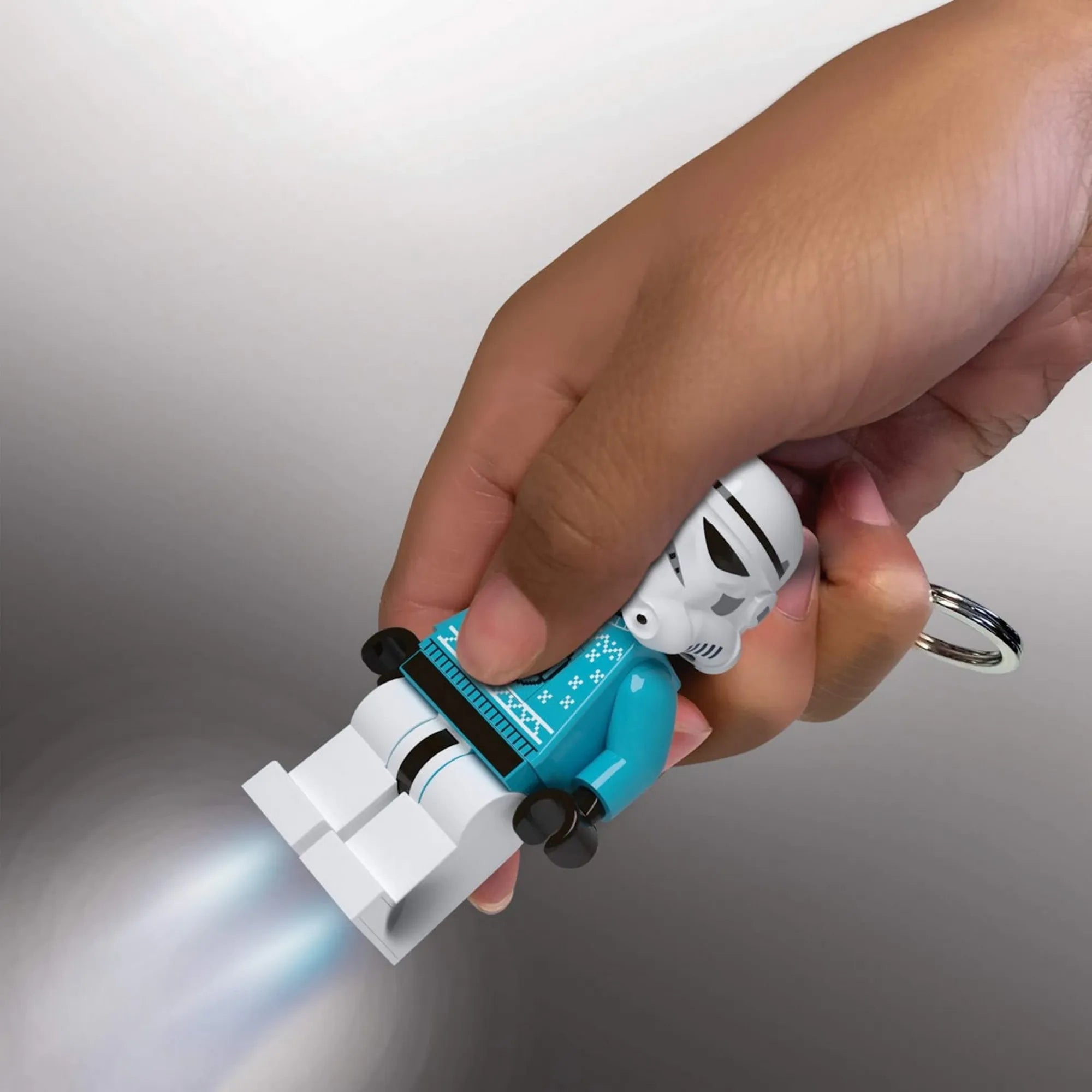 A LEGO Stormtrooper LED kulcstartó kézben tartva, bekapcsolt LED lámpákkal, ahogy erős fényt vet a sötétben.