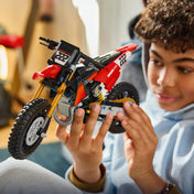 A LEGO Technic: Ducati Desmo450 MX Factory motorkerékpár 42238 modellt egy gyermek kézben tartja és közelről vizsgálja.