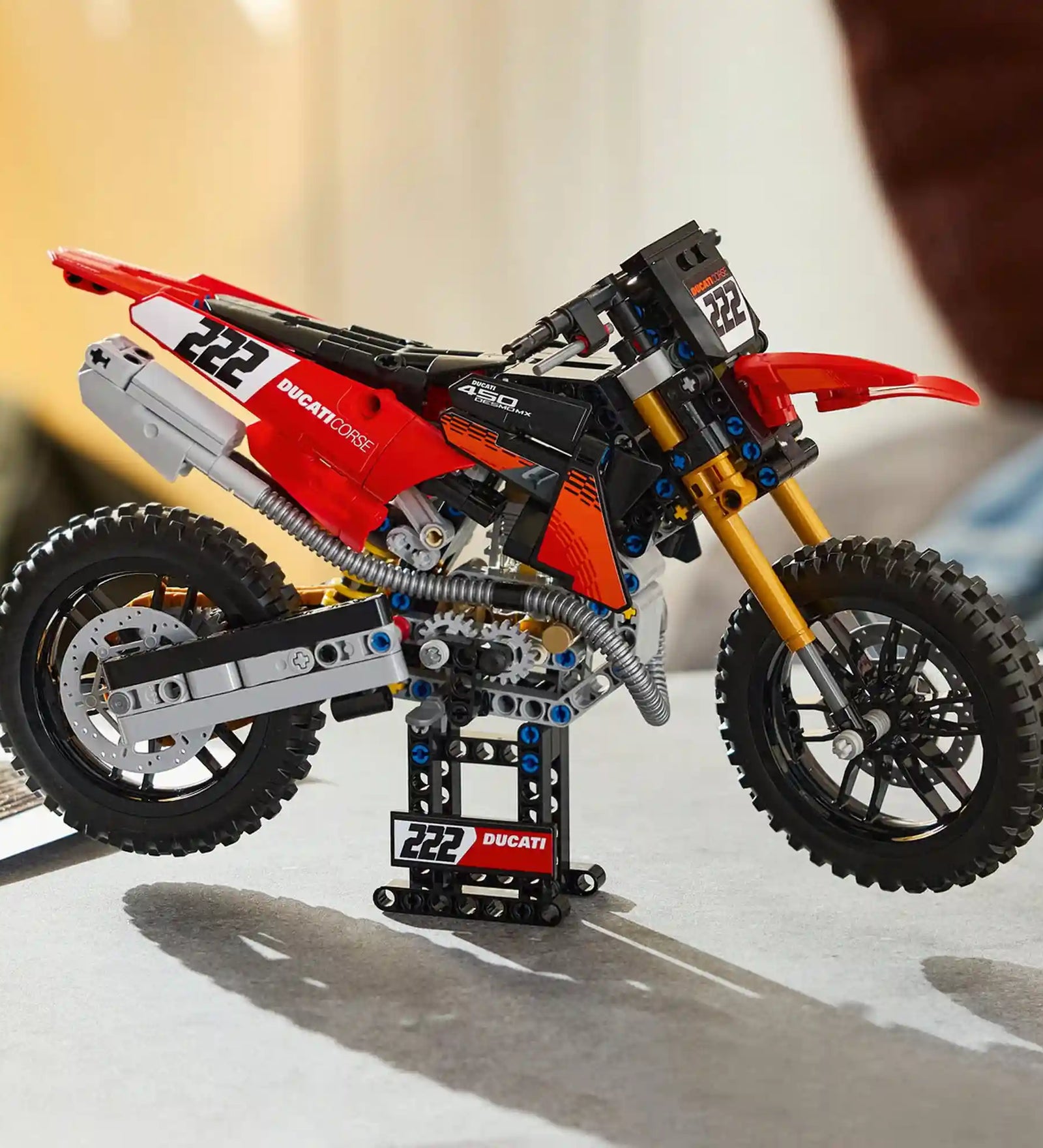 A LEGO Technic: Ducati Desmo450 MX Factory motorkerékpár 42238 megépített modellje a tartóállványon.