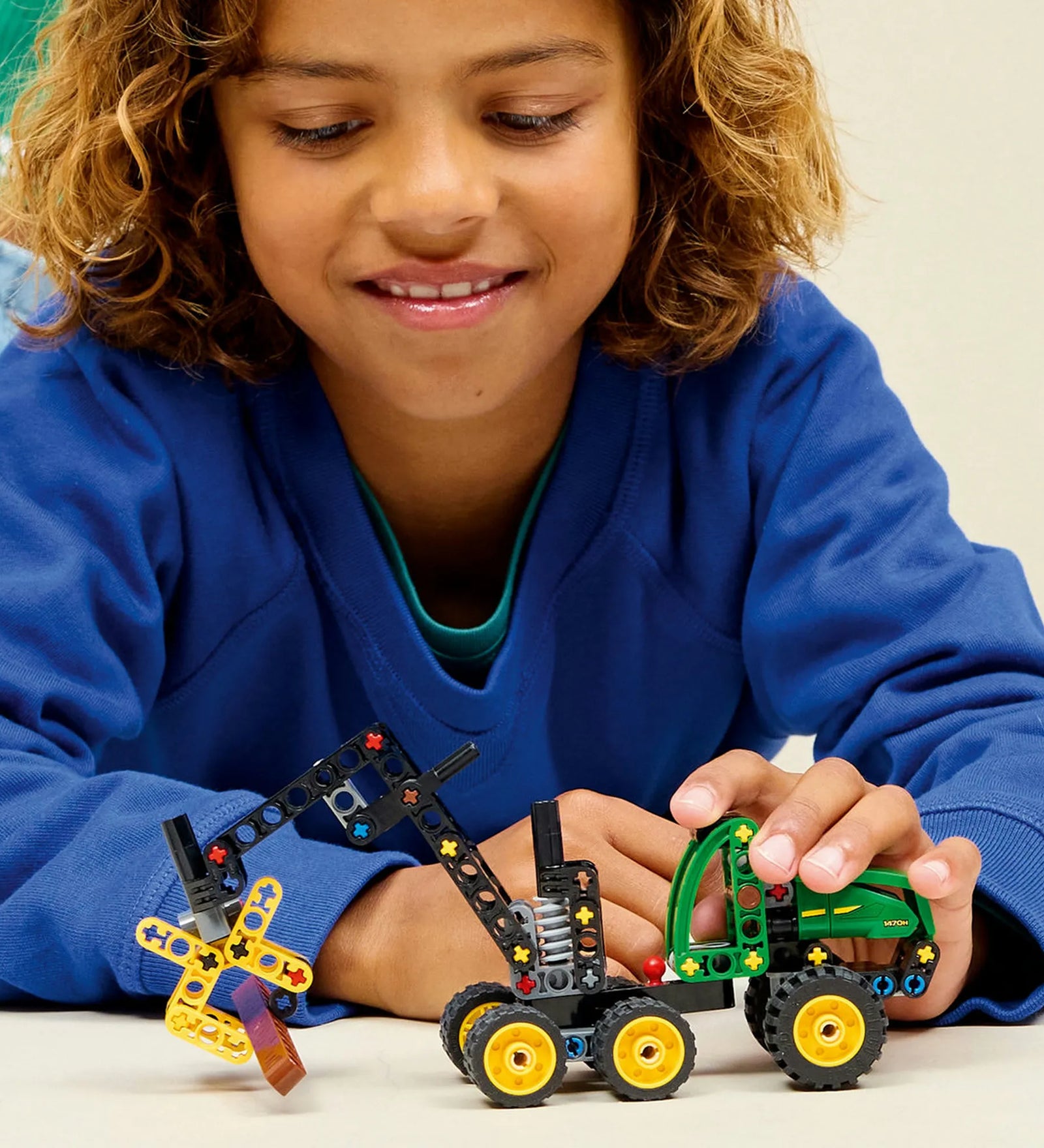 LEGO Technic: John Deere 1470H kerekes betakarítógép 42218 – Gyermek a megépített erdészeti munkagéppel játszik.