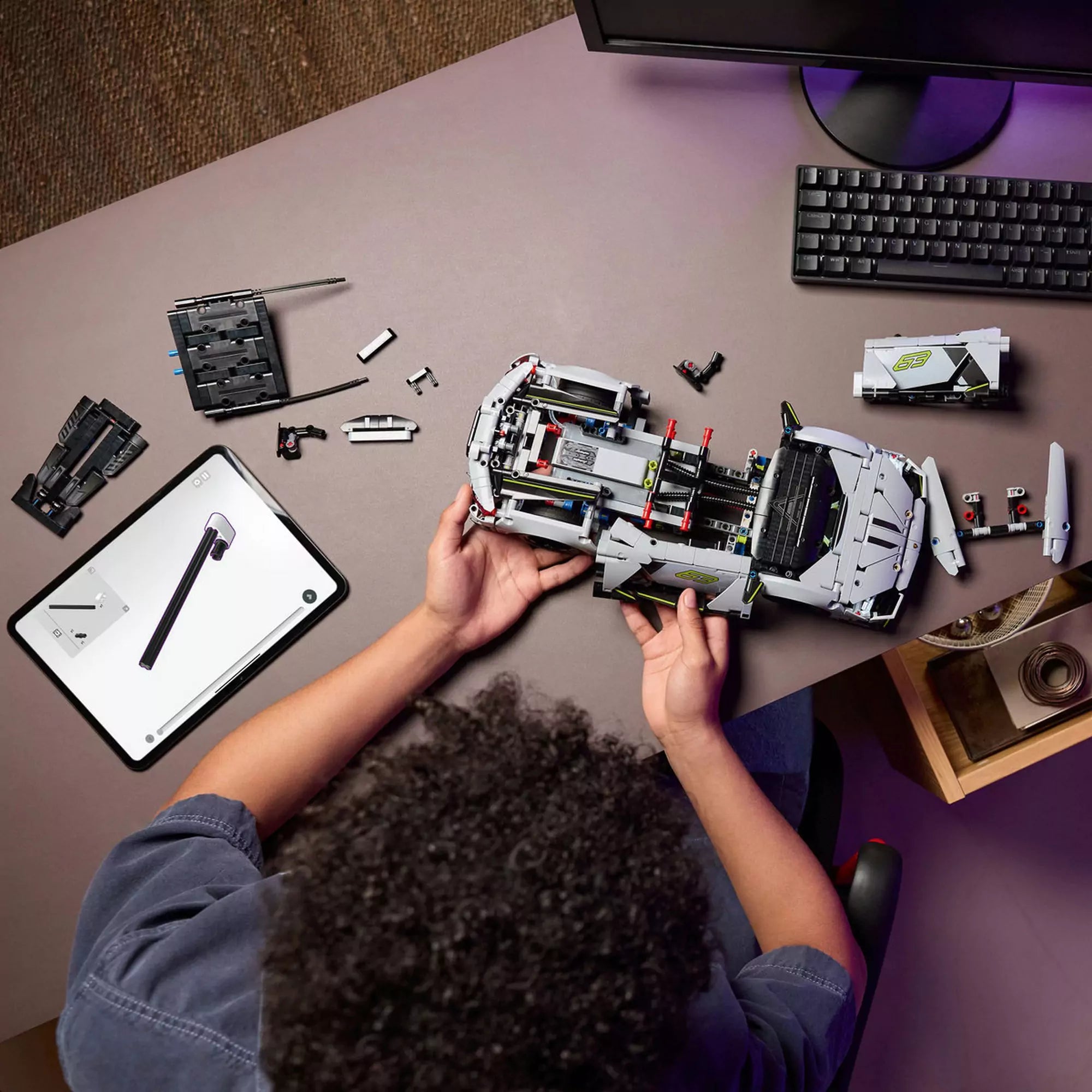 LEGO Technic Lamborghini Revuelto (42214) építés közben – Gyermek rakja össze a sportautót, mellette tableten 3D LEGO útmutató látható.