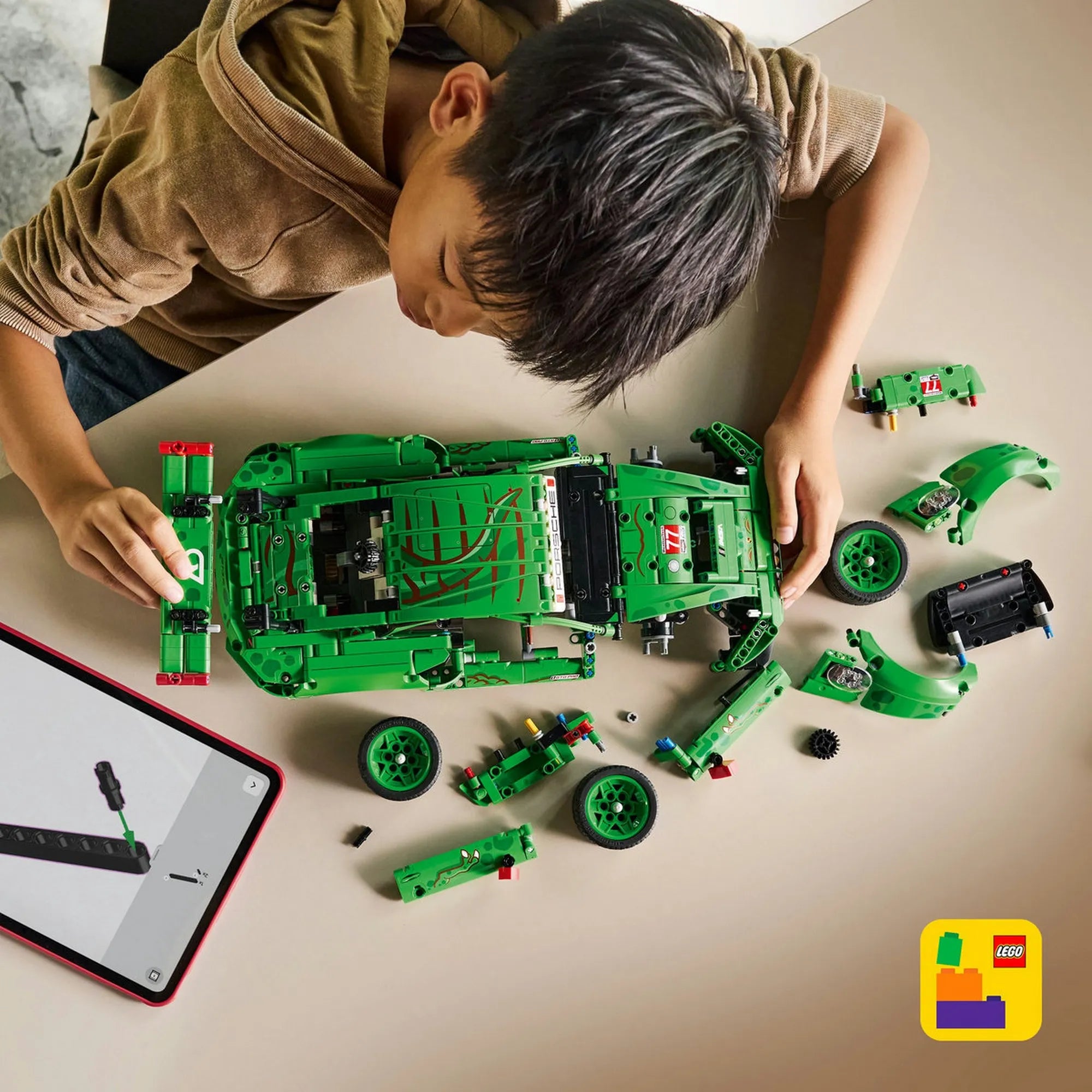 Felülnézetes kép a LEGO Technic Porsche 911 GT3 R REXY AO Racing modellről részben szétszerelve, kerekekkel és karosszériaelemekkel az asztalon