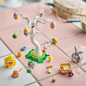 LEGO Tojásvadászat nyuszival és csibével 40808 – Szétszedett és építés közbeni jelenet a tojásfával, figurákkal és kiegészítőkkel rózsaszín felületen.