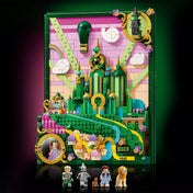 A LEGO Wicked Emerald City falikép teljes, megépített változata: a középen magasodó zöld tornyok, a sárga téglás út, a rózsaszín égbolt és a hőlégballon dominálnak. Jobb felső sarokban Elphaba, bal alsó sarokban Glinda minifigurája jelenik meg dekoratív keretben. Előtérben a hat mellékelt figura sorakozik.