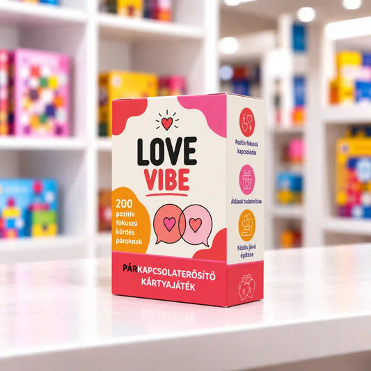 Love Vibe párkapcsolaterősítő kártyajáték piros-rózsaszín doboza egy fehér asztalon, világos, színes játékbolti polcokkal a háttérben.