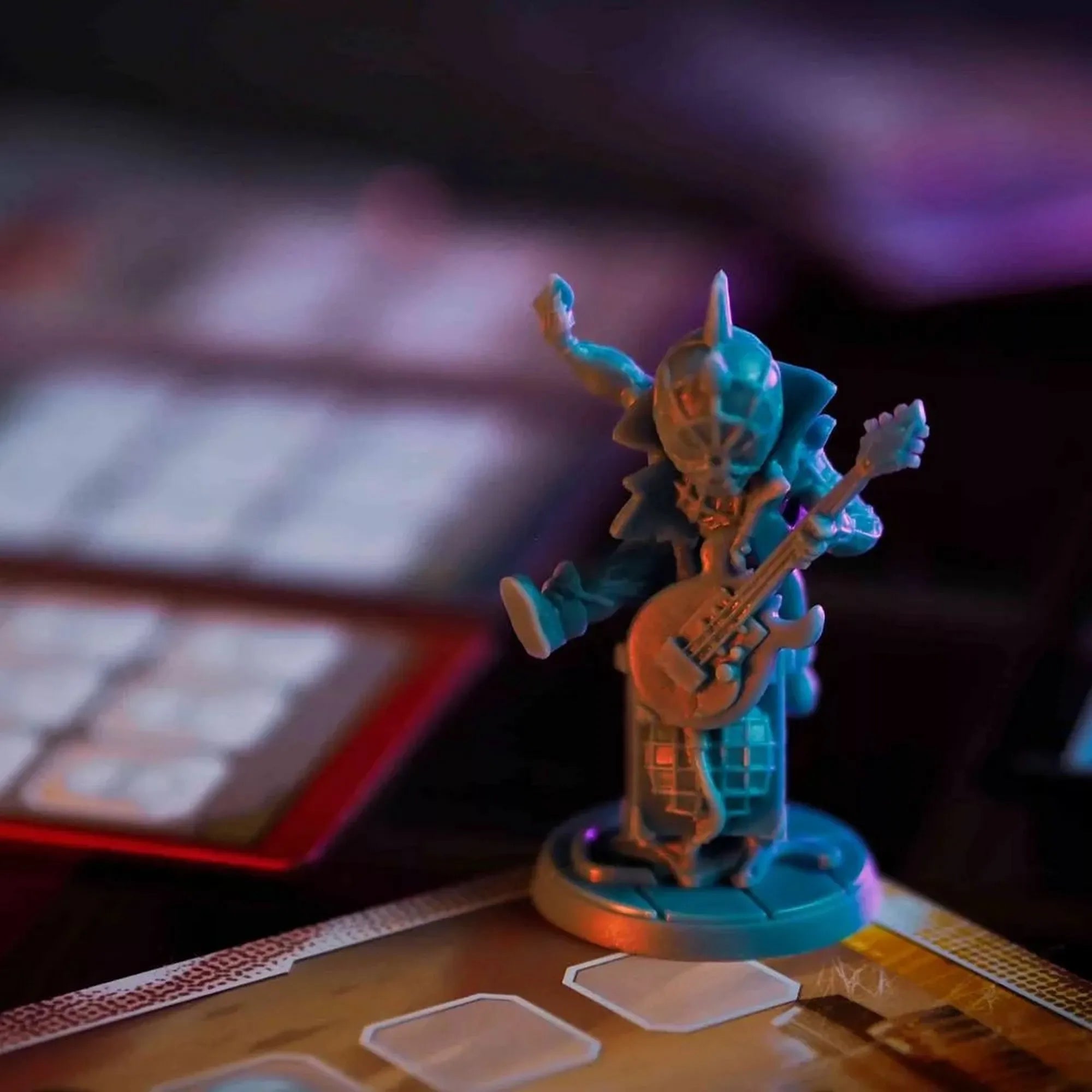 Spider-Punk részletgazdag miniatűr figurája elektromos gitárral, a játéktábla egyik mezőjén, hangulatos színes megvilágításban.