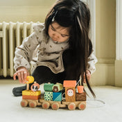Kisgyermek játszik a Djeco Tréning vonat állatfigurákkal (Orange Tree Toys) fából készült szettjével, amely fejleszti a kézügyességet és a színek felismerését.