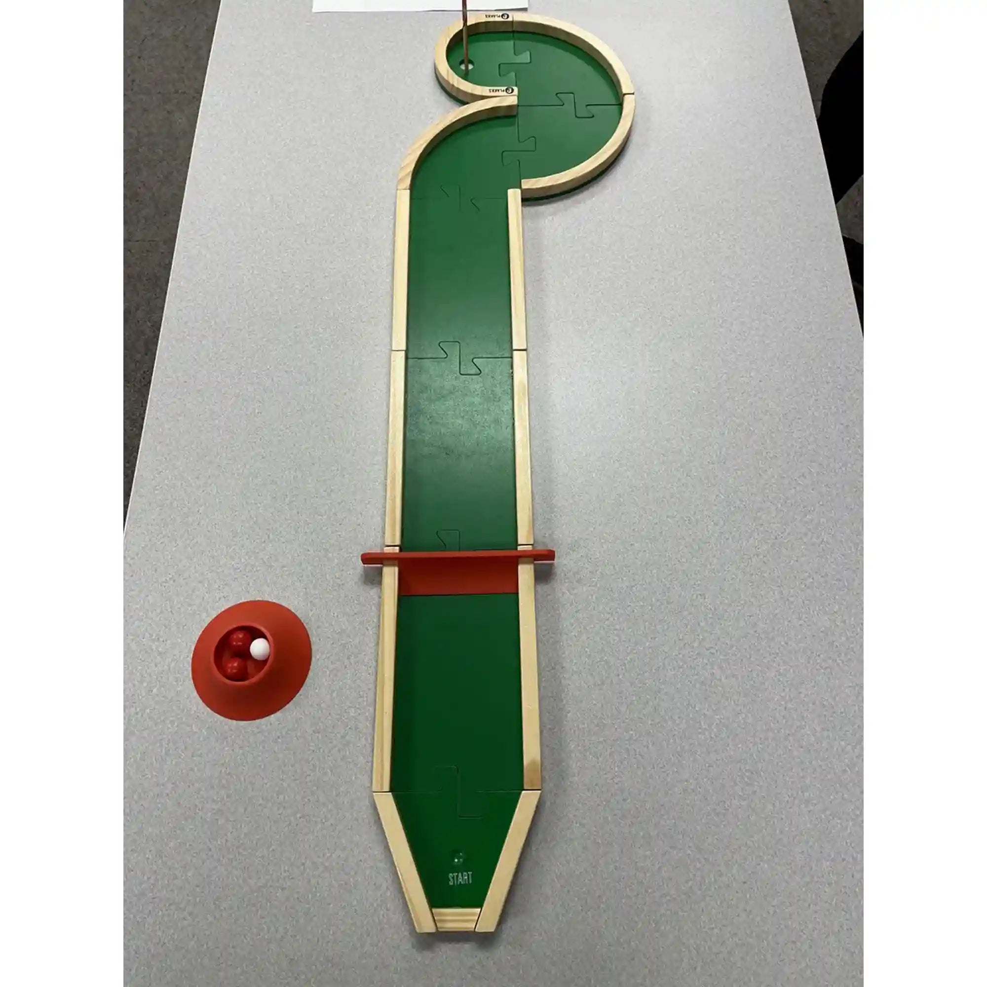 Hosszú, egyenes Pitch & Plakks minigolf pálya több akadállyal.