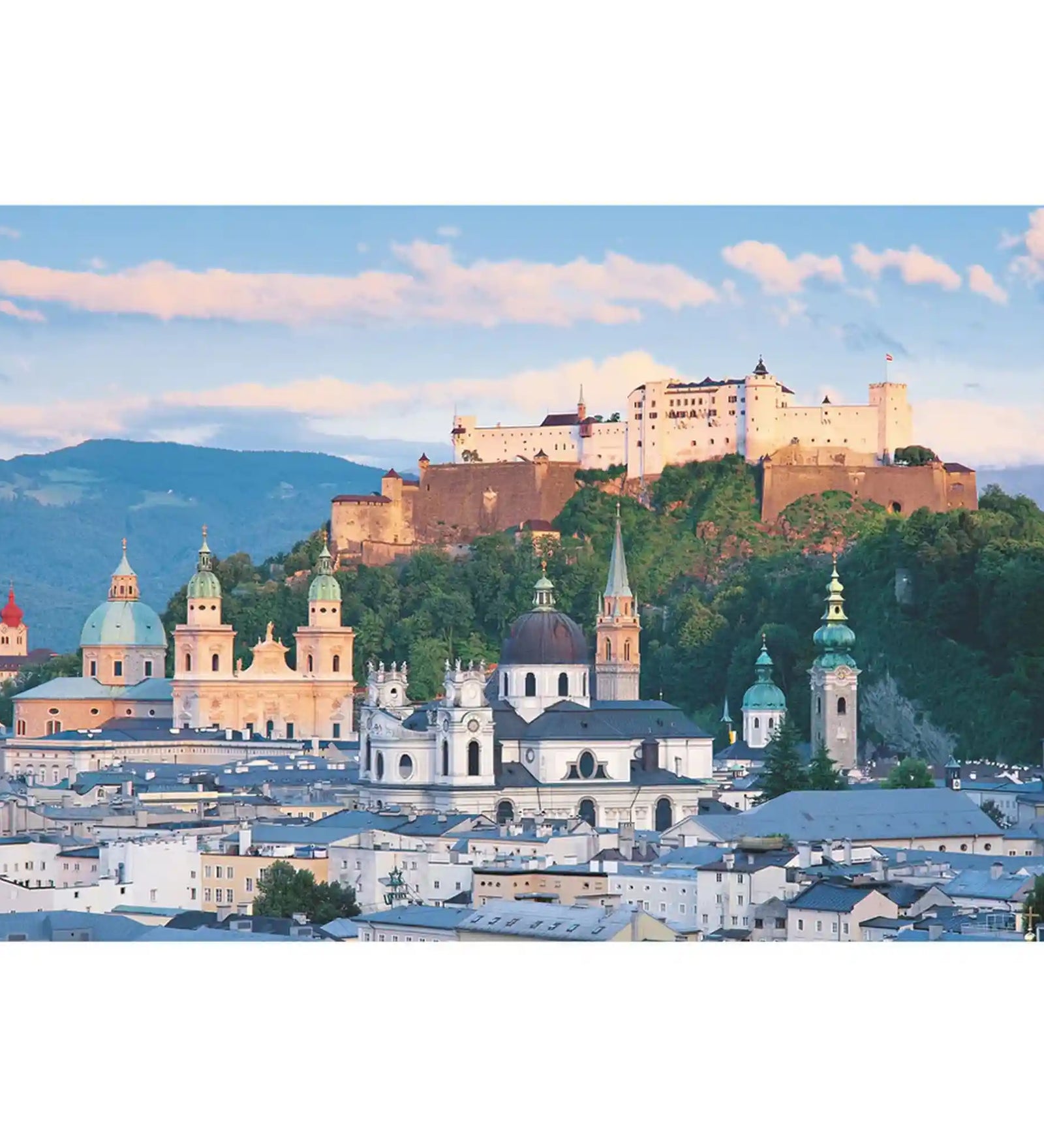 Salzburg város panorámája a híres Hohensalzburg erőddel, történelmi templomtornyokkal és alpesi hegyekkel a háttérben.