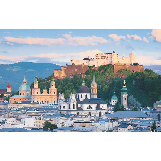 Salzburg város panorámája a híres Hohensalzburg erőddel, történelmi templomtornyokkal és alpesi hegyekkel a háttérben.