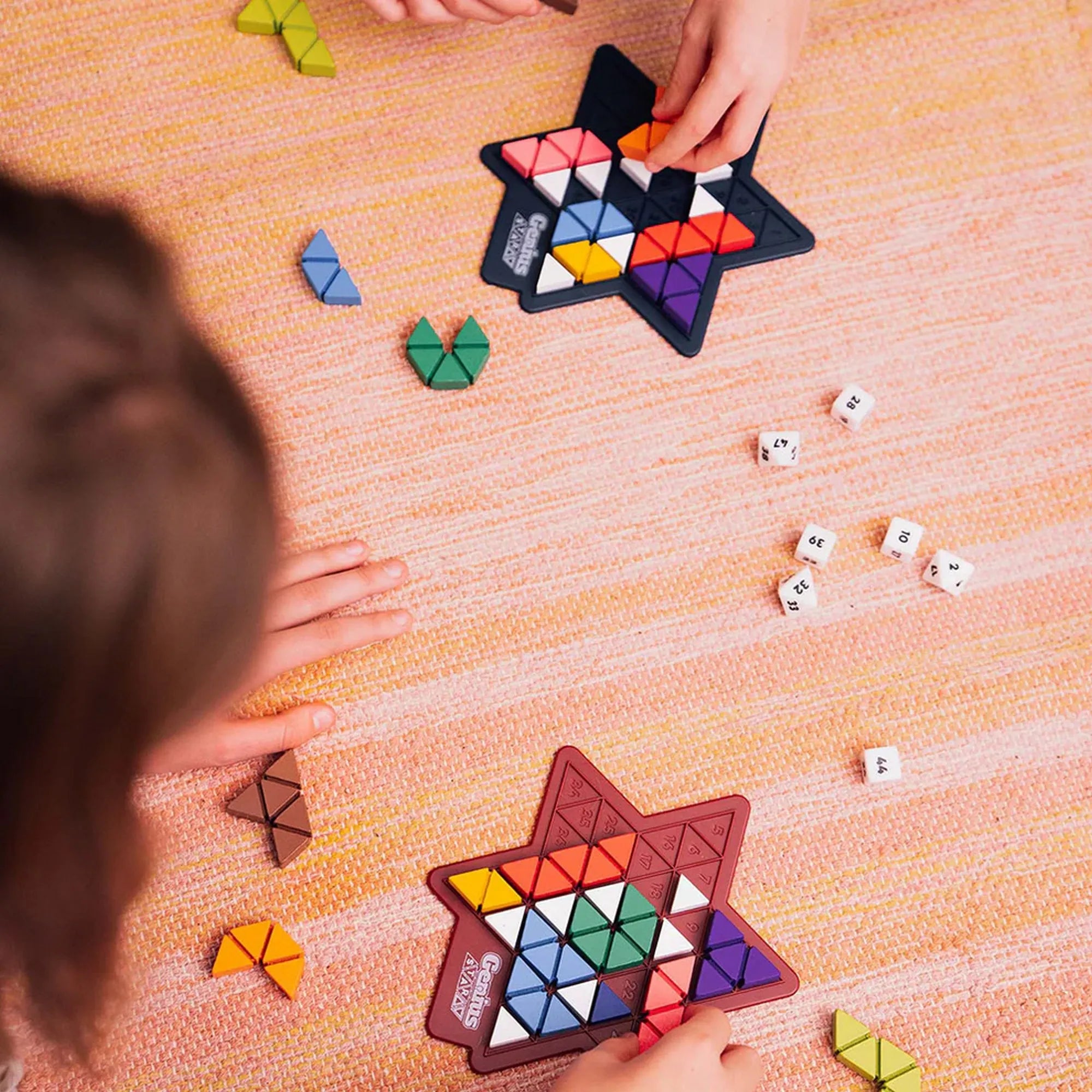 Genius Star logikai társasjáték játék közben, csillag alakú játéktábla színes háromszög és polinom elemekkel, dobókockákkal, gyerekek játék közben.