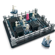 A Smart Games Graveyard Shift játéktábla közelről, csontvázfigurákkal, akadályokkal és a rózsaszín ruhás karakterrel a pálya közepén.